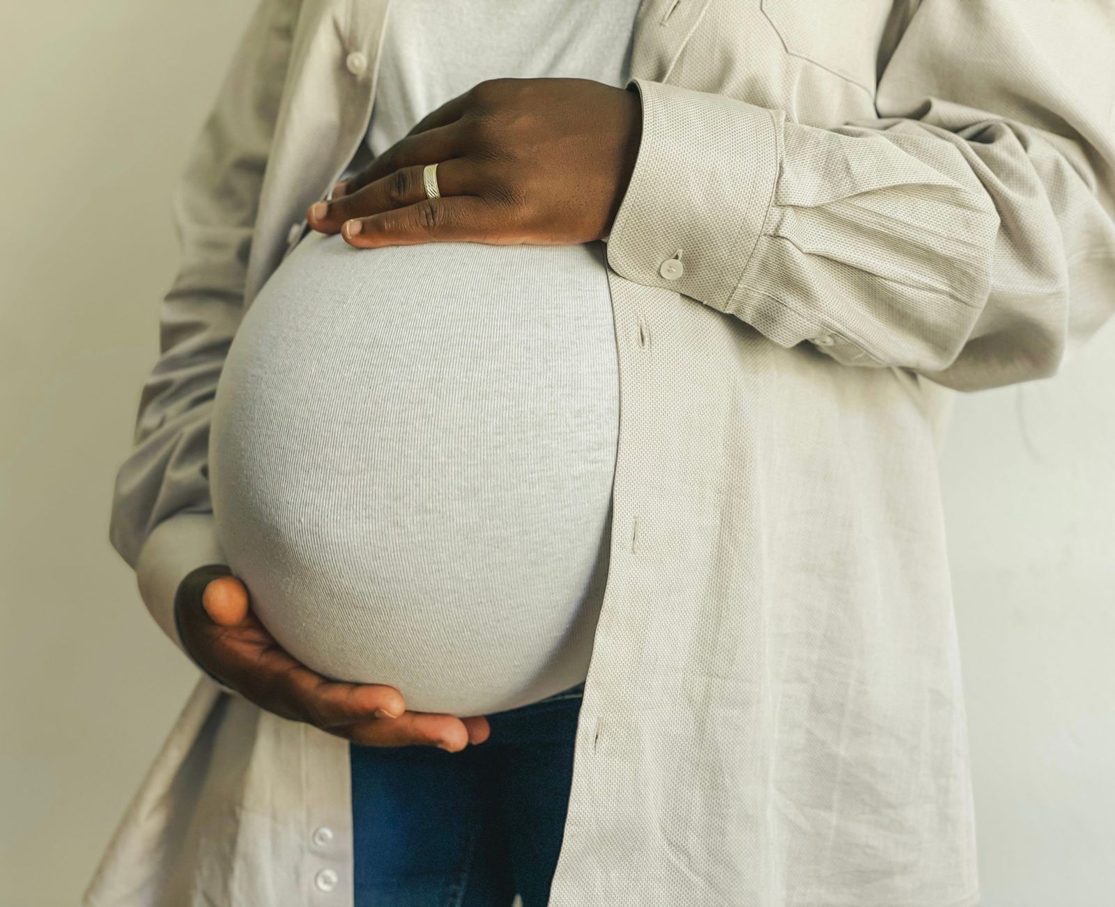 An expectant parent cradling their pregnant belly